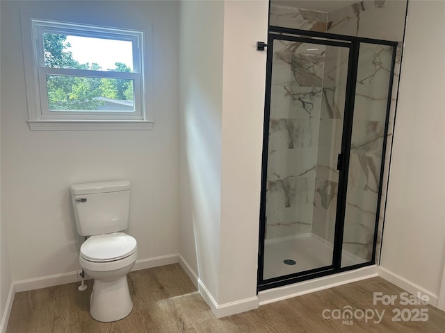 full bathroom featuring toilet, baseboards, a marble finish shower, and wood finished floors