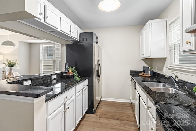kitchen with white cabinetry, stainless steel fridge, light wood-style floors, a peninsula, and range with electric stovetop