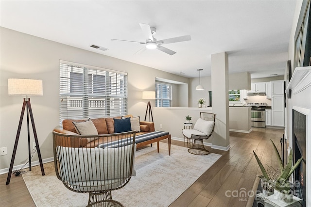 living room with wood finished floors, baseboards, and ceiling fan