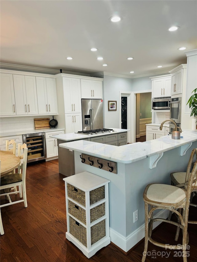 19409 Laurel Glen Ave, Cornelius, NC 28031 - kitchen with ornamental molding, wine cooler, a kitchen island, a breakfast bar area, and appliances with stainless steel finishes