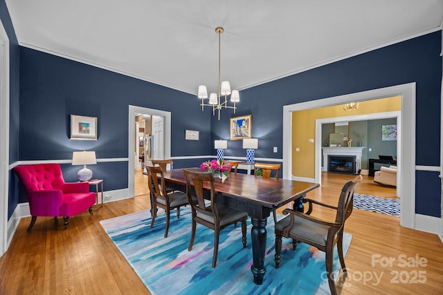100 Poplar Spring Trl, Hendersonville, NC 28739 - dining space featuring wood finished floors, a chandelier, a glass covered fireplace, and crown molding