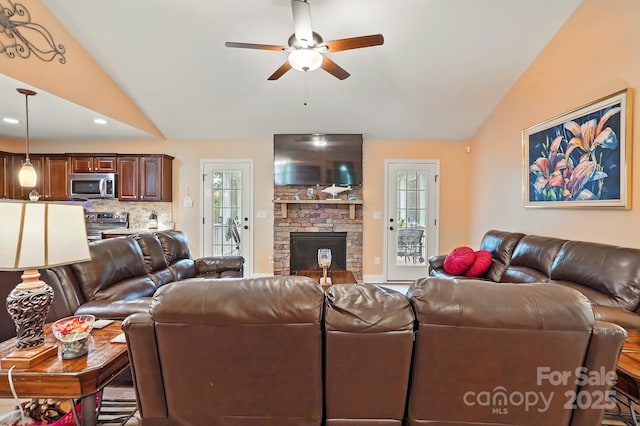 living area with a stone fireplace, a ceiling fan, vaulted ceiling, and recessed lighting
