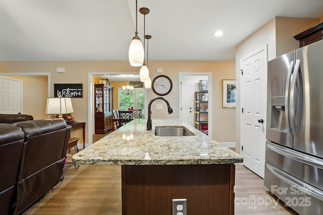 kitchen with a notable chandelier, a sink, stainless steel fridge with ice dispenser, light wood-style floors, and pendant lighting