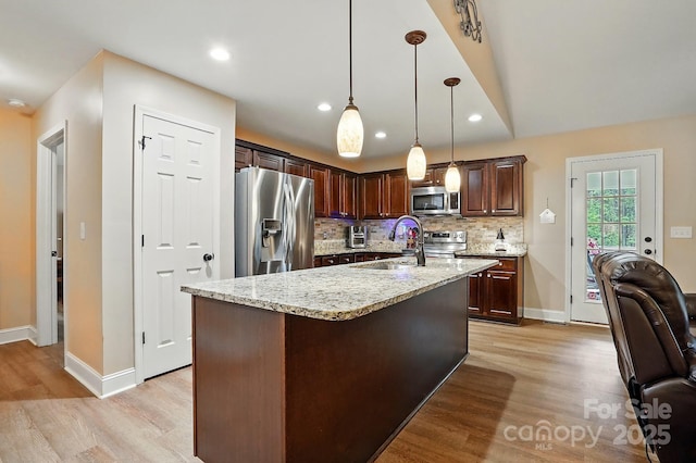 kitchen with baseboards, backsplash, stainless steel appliances, and light wood-type flooring