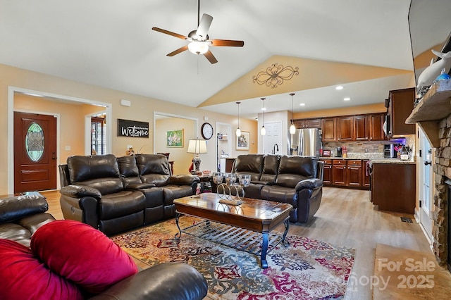living room featuring a ceiling fan, high vaulted ceiling, and light wood finished floors