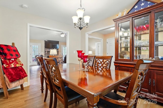dining area with light wood finished floors and ceiling fan with notable chandelier