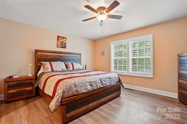 bedroom featuring baseboards, a ceiling fan, wood finished floors, and visible vents