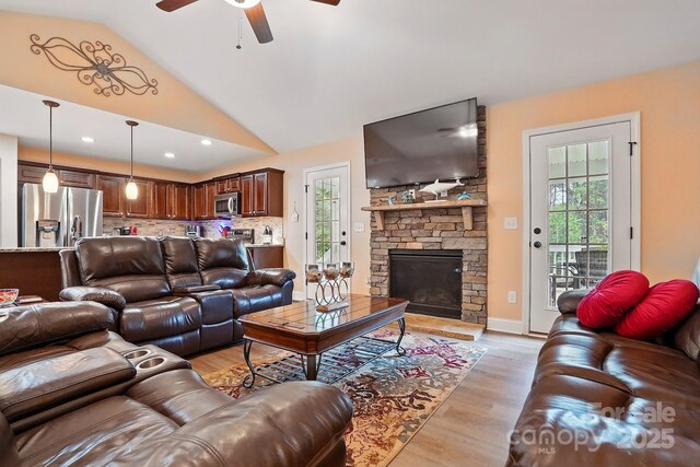 living area with a healthy amount of sunlight, ceiling fan, light wood-style floors, and lofted ceiling