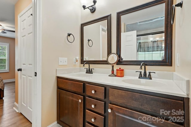 full bathroom with double vanity, a sink, a ceiling fan, and wood finished floors