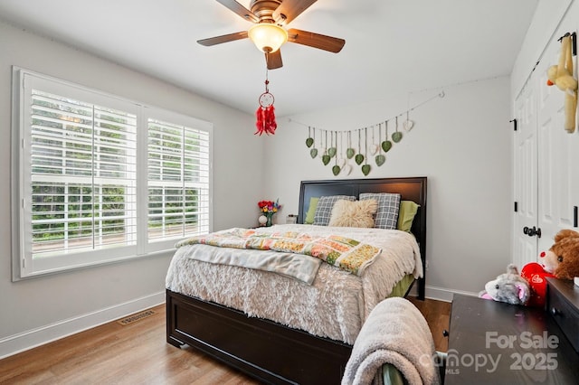 bedroom with baseboards, a ceiling fan, wood finished floors, and a closet