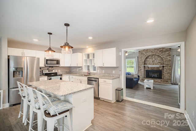 1211 Mirror Park Dr, Salisbury, NC 28146 - kitchen with light stone counters, appliances with stainless steel finishes, a kitchen island, white cabinets, and a sink