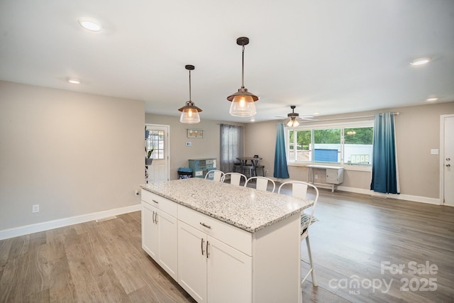 1211 Mirror Park Dr, Salisbury, NC 28146 - kitchen with a kitchen breakfast bar, ceiling fan, white cabinetry, a kitchen island, and pendant lighting