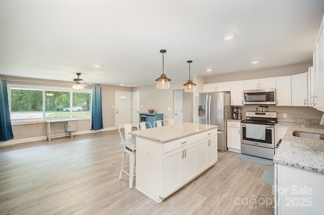1211 Mirror Park Dr, Salisbury, NC 28146 - kitchen featuring a breakfast bar area, white cabinets, stainless steel appliances, a center island, and light wood finished floors