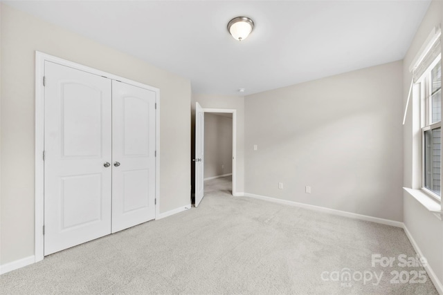 unfurnished bedroom featuring carpet, baseboards, and a closet