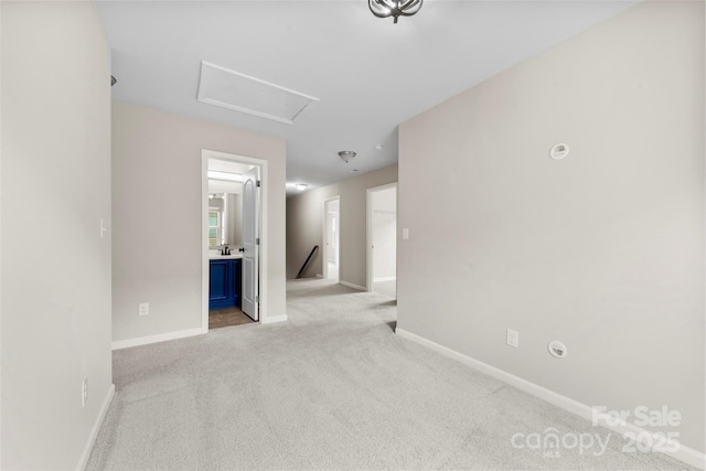 empty room featuring carpet flooring, baseboards, and attic access