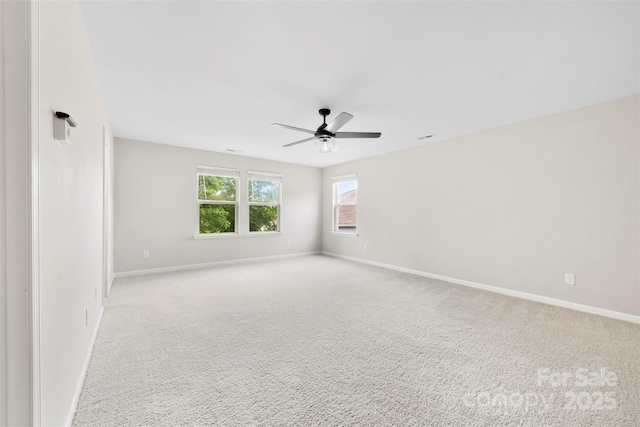 unfurnished room featuring a ceiling fan, baseboards, and light carpet