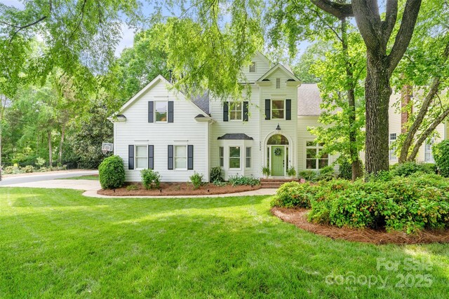 colonial home with a shingled roof and a front yard