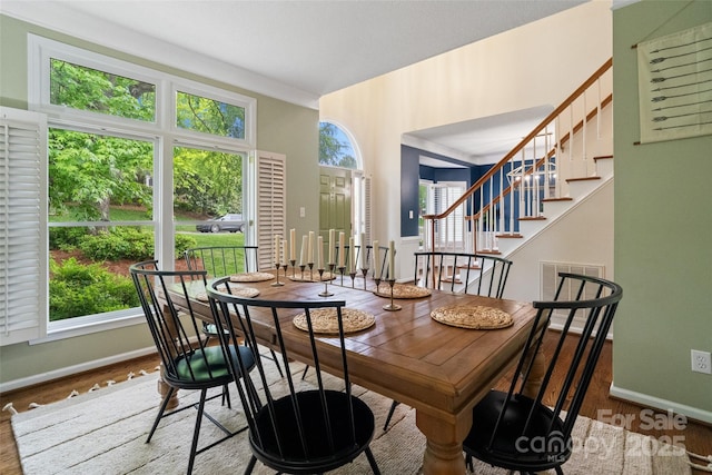dining room with stairs, visible vents, wood finished floors, and baseboards