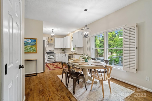 dining area with a notable chandelier, baseboards, wood finished floors, and plenty of natural light
