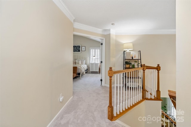 hallway featuring baseboards, an upstairs landing, carpet, and crown molding