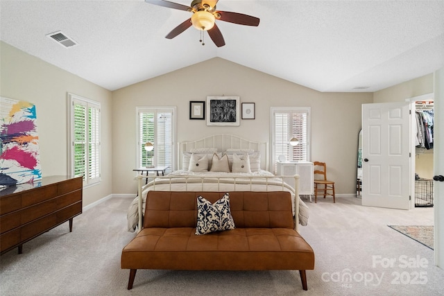 bedroom featuring visible vents, light carpet, multiple windows, and lofted ceiling