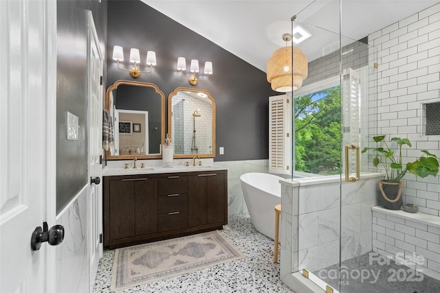 bathroom featuring tile walls, a sink, a shower stall, a freestanding bath, and double vanity