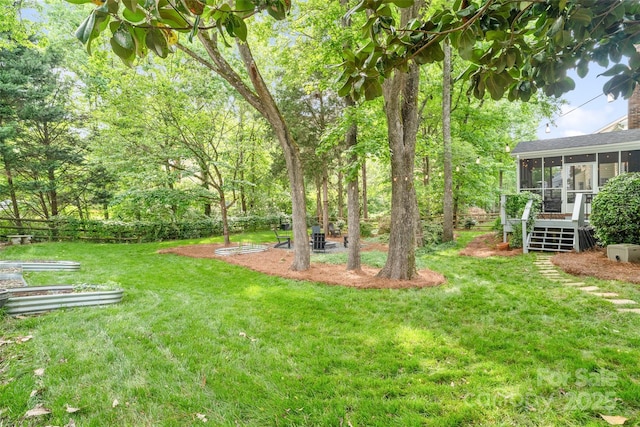 view of yard with a sunroom and a garden