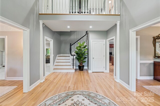 1721 White Pond Ln, Waxhaw, NC 28173 - entrance foyer with wood finished floors, baseboards, a towering ceiling, stairway, and ornate columns
