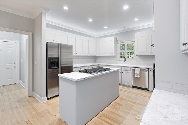 1721 White Pond Ln, Waxhaw, NC 28173 - kitchen with stainless steel appliances, ornamental molding, light wood-type flooring, a center island, and white cabinets