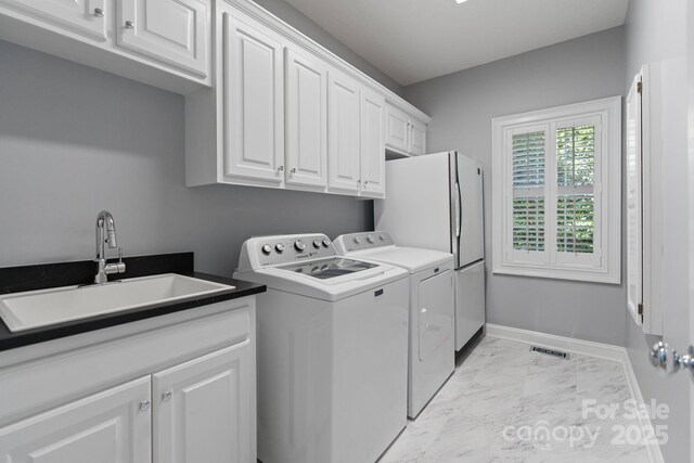 1721 White Pond Ln, Waxhaw, NC 28173 - laundry room featuring washing machine and clothes dryer, light marble finish flooring, cabinet space, and baseboards