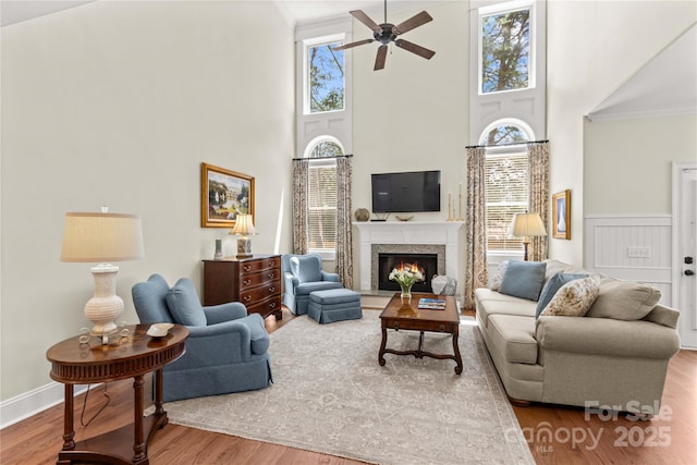 7923 Mountain Shore Dr, Sherrills Ford, NC 28673 - living room featuring wood finished floors, a ceiling fan, a towering ceiling, crown molding, and a high end fireplace