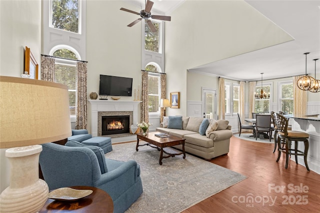 7923 Mountain Shore Dr, Sherrills Ford, NC 28673 - living area featuring a chandelier, wood finished floors, a warm lit fireplace, crown molding, and ceiling fan