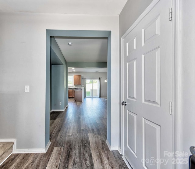 hall with dark wood-style flooring and baseboards