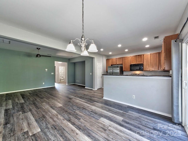 kitchen featuring recessed lighting, freestanding refrigerator, dark countertops, black microwave, and dark wood-type flooring