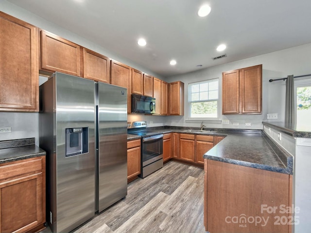 kitchen featuring a sink, stainless steel appliances, visible vents, dark countertops, and plenty of natural light