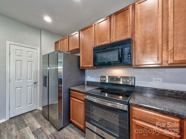 kitchen featuring dark countertops, wood finished floors, stainless steel appliances, and brown cabinetry