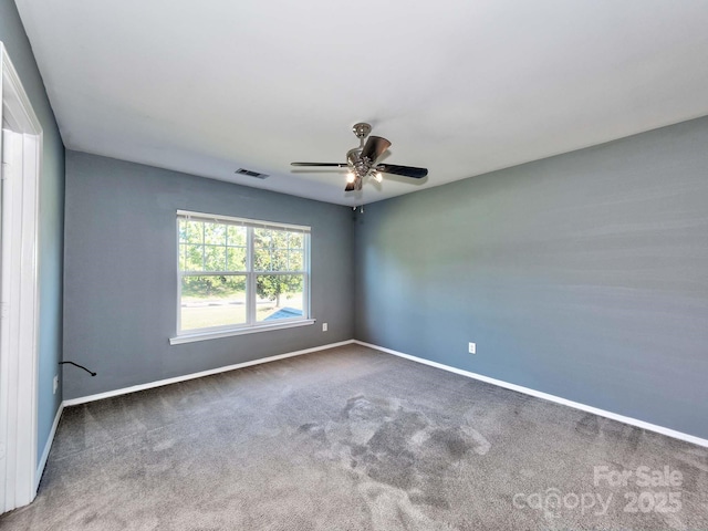 carpeted spare room with visible vents, a ceiling fan, and baseboards