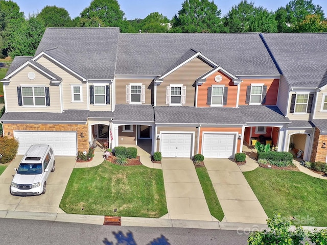 view of front of home featuring roof with shingles, a front yard, concrete driveway, and an attached garage