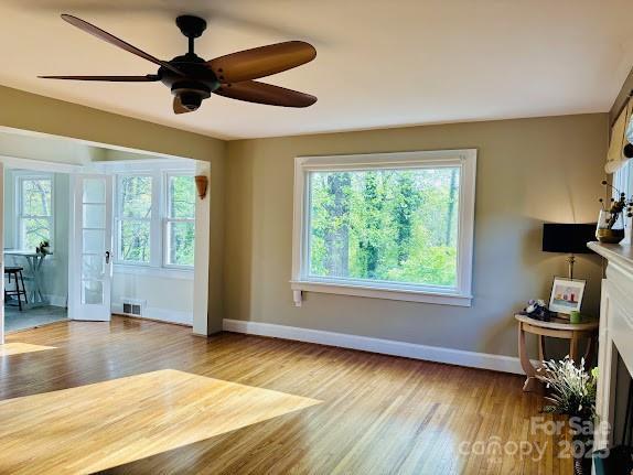 living room with baseboards, wood finished floors, and a ceiling fan
