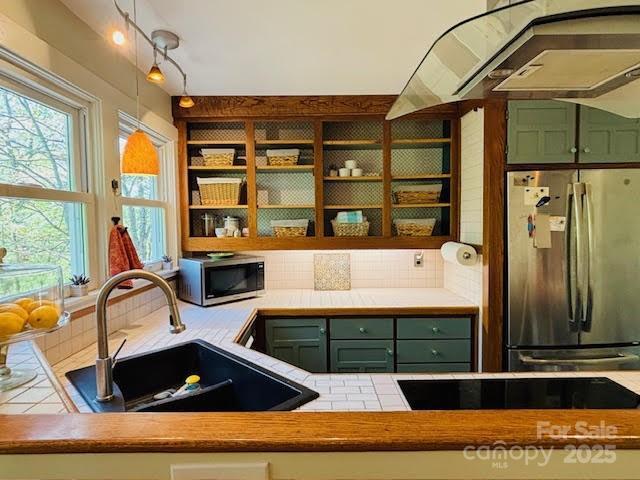 kitchen with stainless steel appliances, green cabinets, a sink, and tasteful backsplash