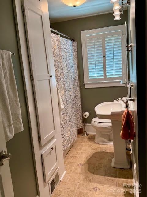 bathroom with toilet, tile patterned floors, baseboards, and curtained shower
