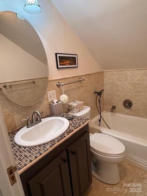 full bath with a bathtub, toilet, vanity, tile patterned floors, and vaulted ceiling