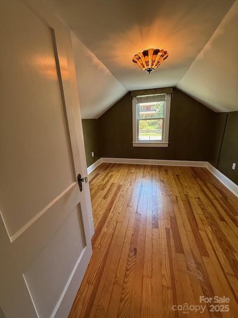 bonus room featuring hardwood / wood-style flooring, lofted ceiling, and baseboards