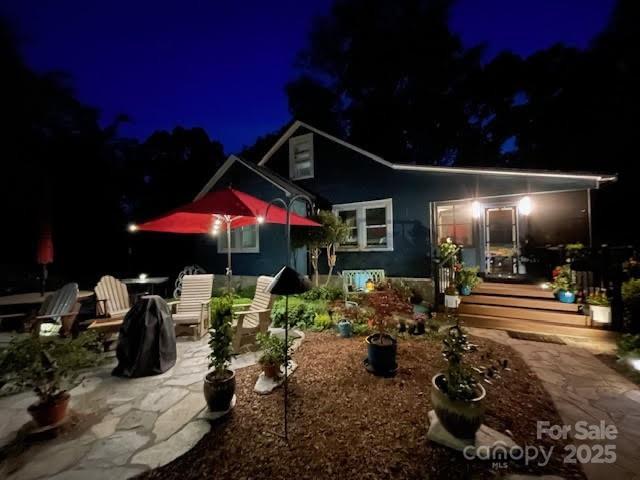 back of house at night featuring a patio area