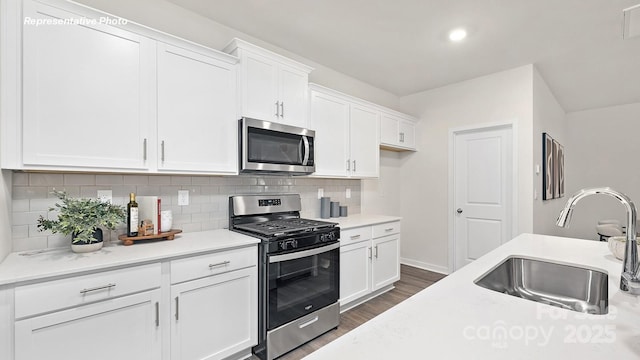 kitchen with light countertops, a sink, stainless steel appliances, and dark wood-type flooring