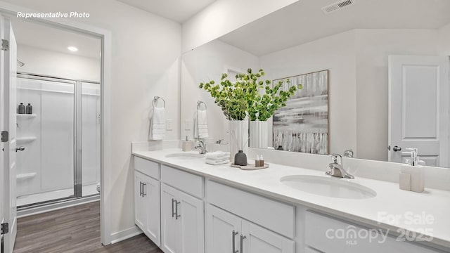 bathroom featuring a sink, visible vents, a shower stall, and wood finished floors