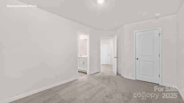 unfurnished bedroom featuring baseboards, light carpet, and ensuite bathroom