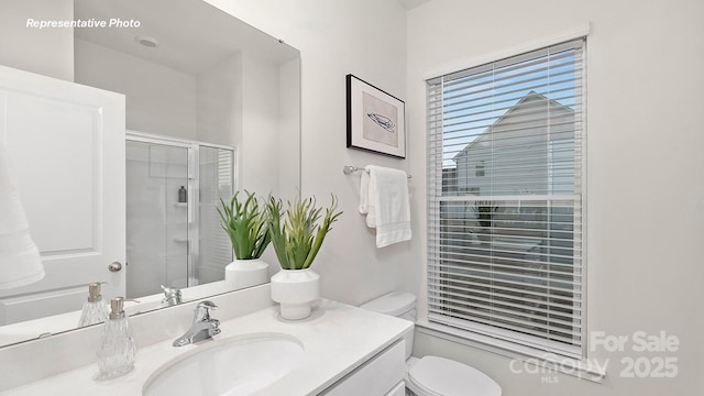 bathroom with toilet, a stall shower, and vanity
