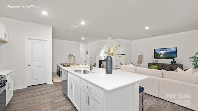 kitchen with a sink, stainless steel appliances, open floor plan, white cabinetry, and wood finished floors