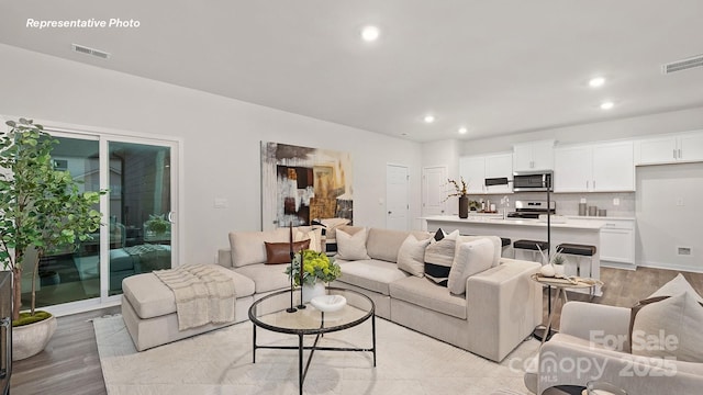 living area with visible vents, recessed lighting, and light wood-style flooring